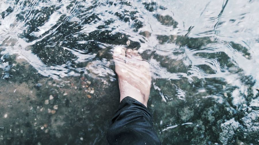 Low section of man standing in water