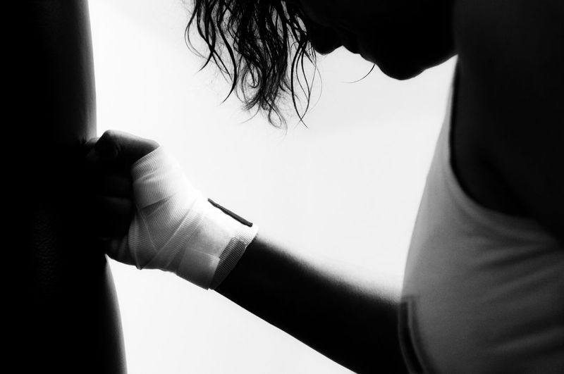 Midsection of woman practicing boxing against white background