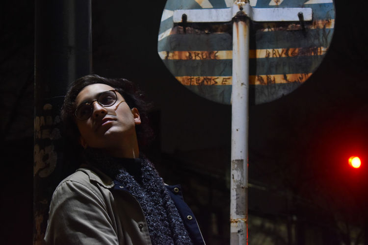 Young man against road sign at night