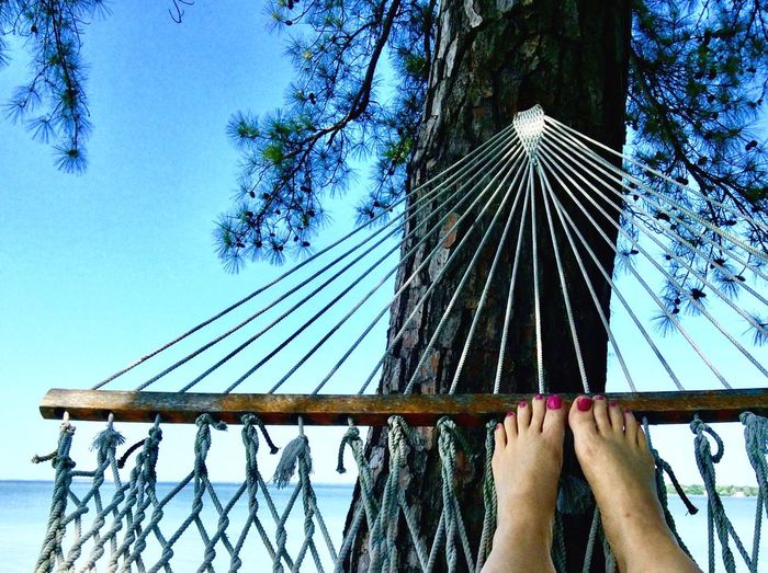 Low section of woman resting in hammock against sea