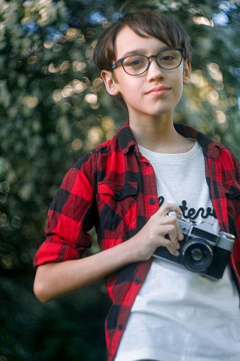 Portrait of boy wearing eyeglasses holding camera