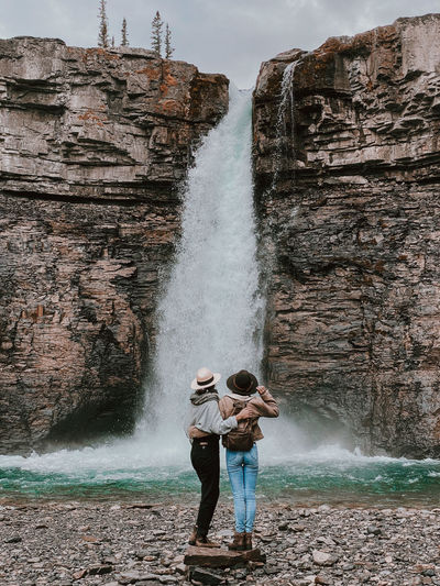 Full length of friends standing on rock