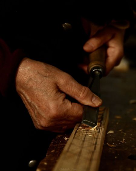 Cropped hands of carpenter using chisel on wood