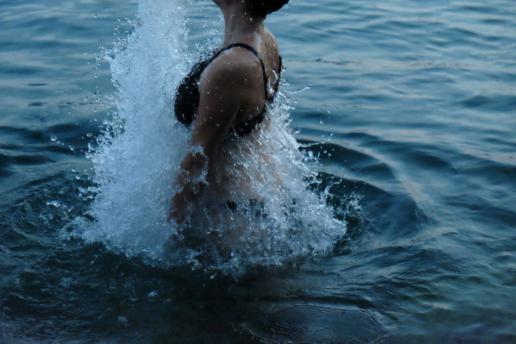 Midsection of woman splashing water in lake