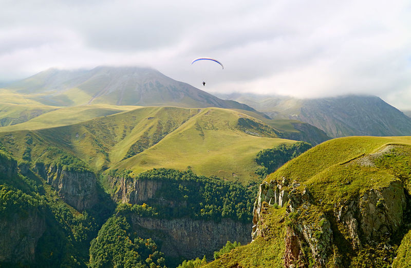 Paragliding over the lush caucasus mountain ranges, georgian military highway, gudauri town, georgia