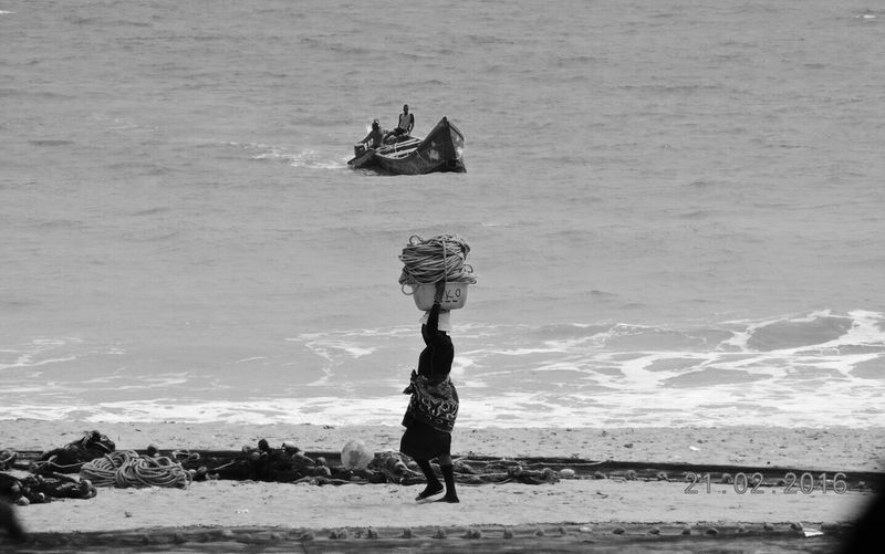 High angle view of carrying fishing container on head at beach