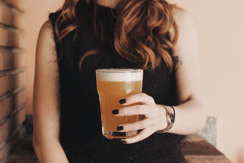 Midsection of woman holding beer glass