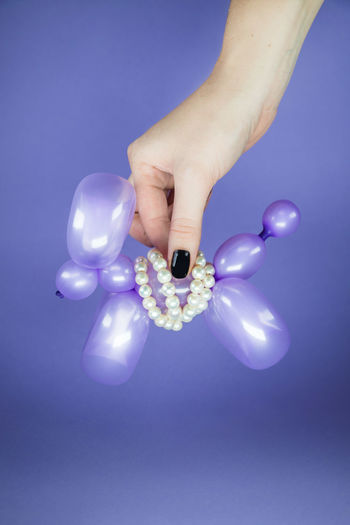 Close-up of hand holding balloons against blue background