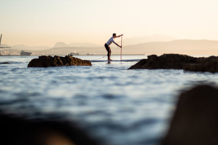 Full length of man standing on paddleboard in sea