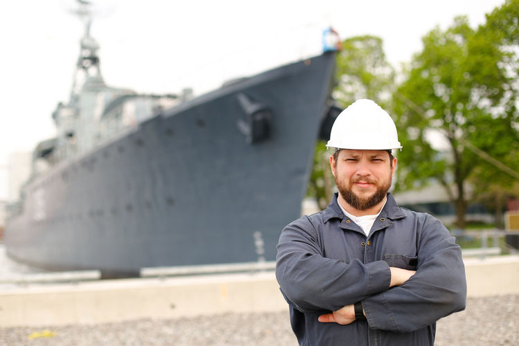 Portrait of seaman standing against ship