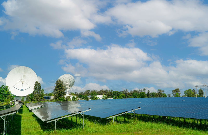 Solar farm and green field with blue sky. big satellite dish near solar farm. solar power green 