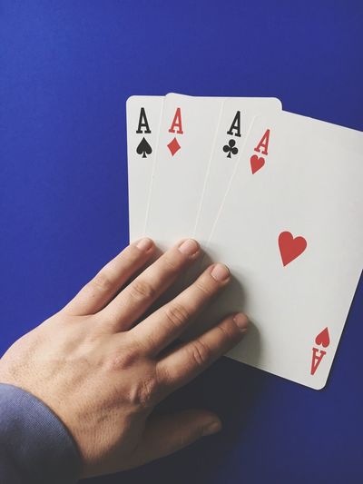 High angle view of man with three aces cards on blue table