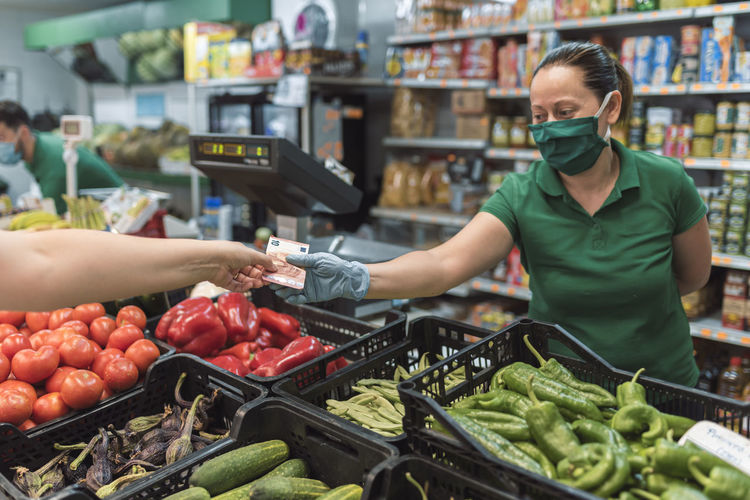 A fruit woman receiving payment in euros from a client