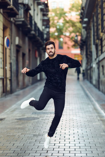 Full length portrait of young man jumping on street