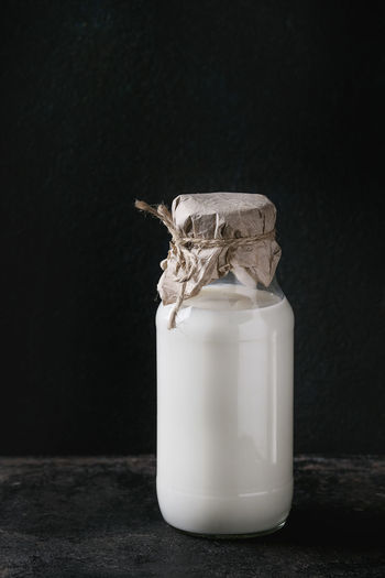 Close-up of white jar on table against black background