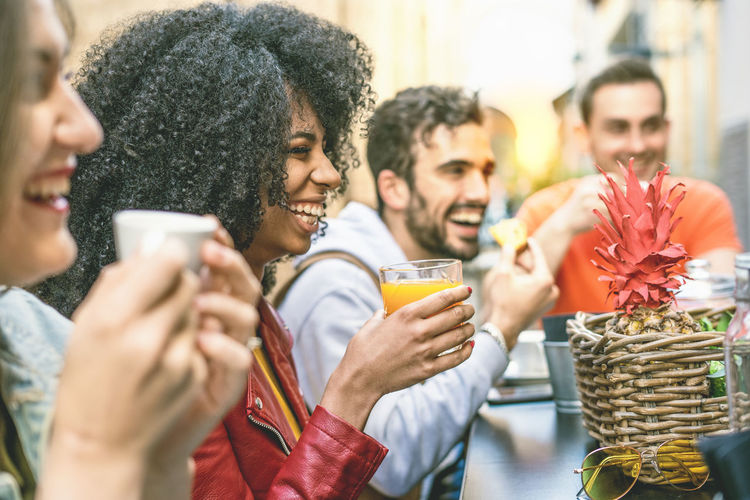 People holding drinks and food at table