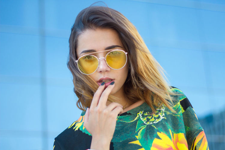 Fashionable young woman wearing top and sunglasses in city