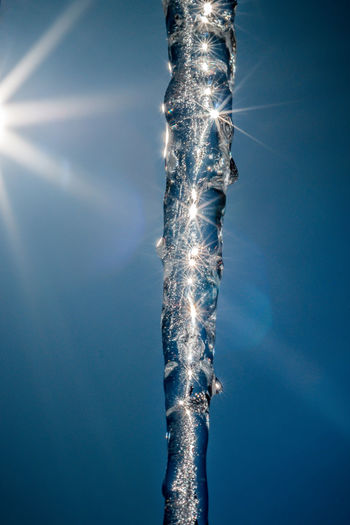 Close-up of icicle against sky on sunny day