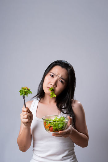 Portrait of woman holding food against white background
