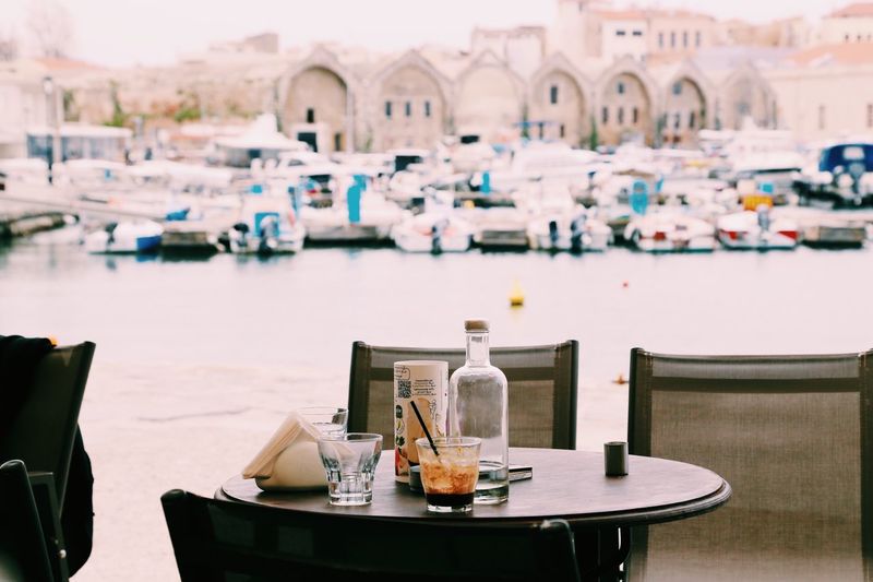 Empty chairs and tables at outdoors restaurant in a harbor in chania 