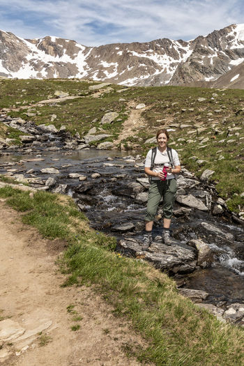 Woman standing by stream against mountain