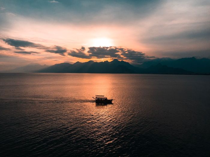 Boat in sea against sky during sunset