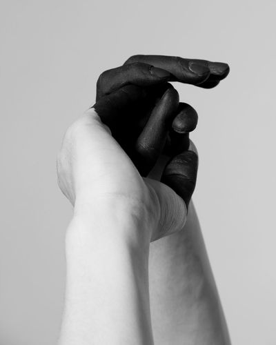 Close-up of man holding hands against white background