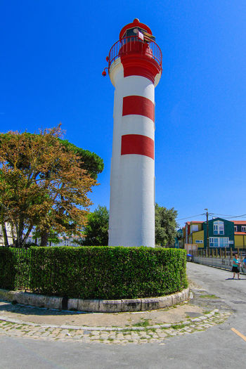 Lighthouse against blue sky and building