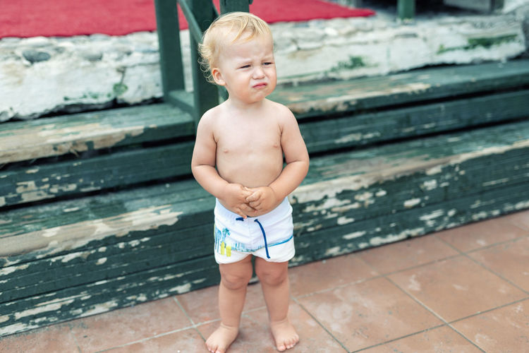 Full length of shirtless boy crying while standing outdoors