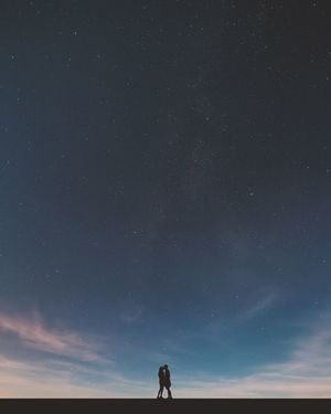 Silhouette couple kissing against sky at night