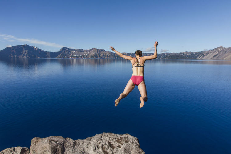 A young woman jumps in the cold, clear waters of crater lake.