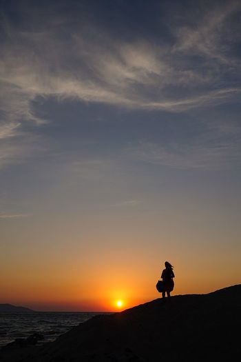 Silhouette man standing on shore against sky during sunset
