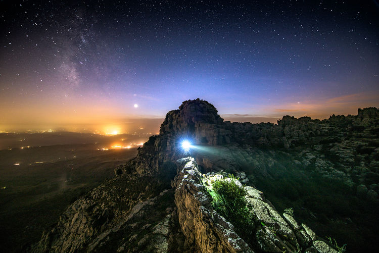 Scenic view of illuminated rock formation against sky at night