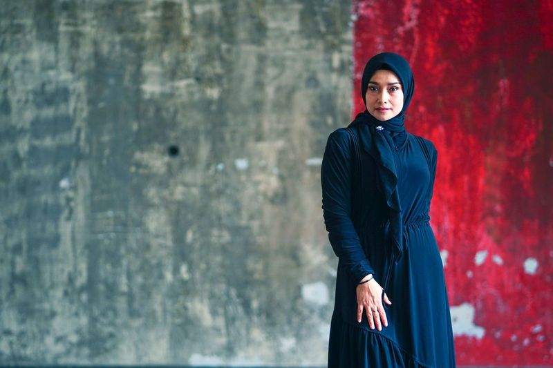 Beautiful indonesian woman wearing a black hijab against the rustic wall as a background