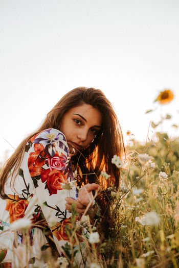 Portrait of beautiful young woman with flowers in sunlight