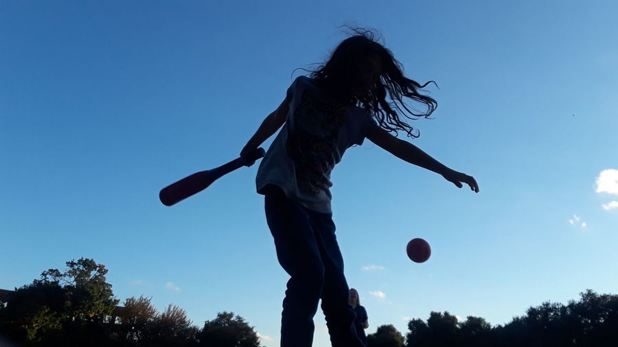 Low angle view of person playing ball against clear blue sky