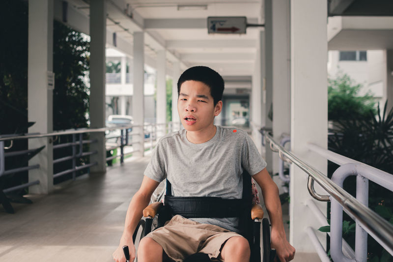 Asian special child on wheelchair  on ramp for disabled people background in hospital,.