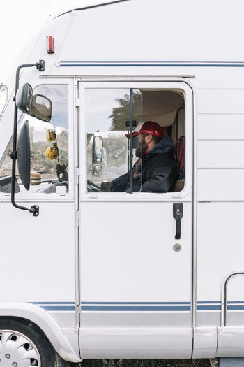 Side view of warm dressed man with hat driving a camp van