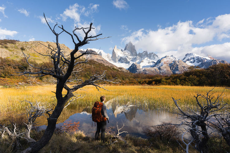 Full length of woman on snowcapped mountains by lake against sky