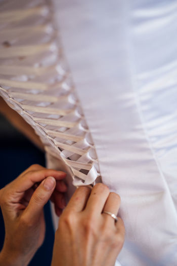 Cropped hands of bridesmaid tying lace of dress