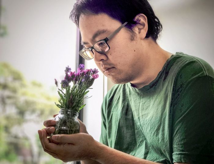 Young man smelling lavender flowers in glass jar