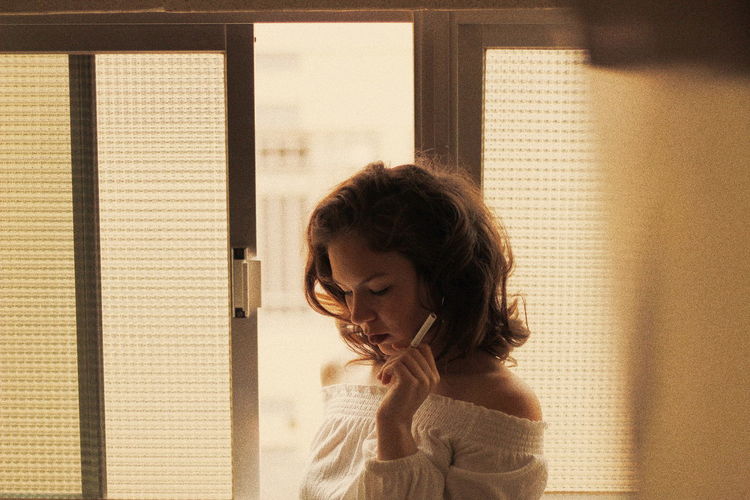 Woman smoking cigarette by window
