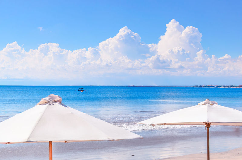Beach umbrellas at calm blue sea backdrop. concept of an ideal tropic exotic vacation. 