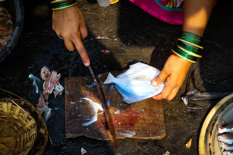 Cropped hands of woman cutting fish in market