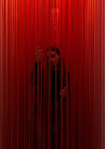 Portrait of woman standing amidst red curtain