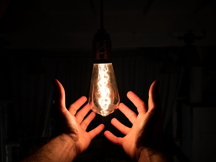 Midsection of person holding light bulb
