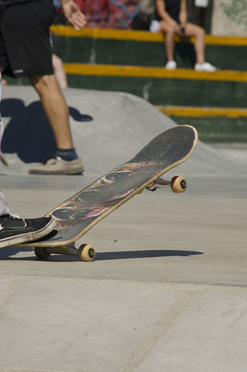 Low section of person with skateboard by people outdoors