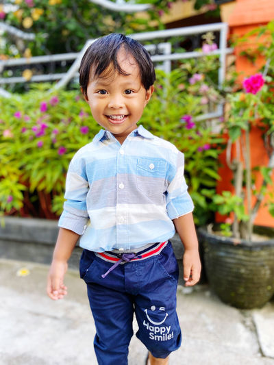 Portrait of boy standing on footpath
