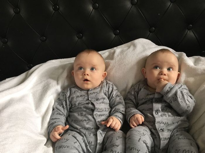 Cute twin baby boys sitting on bed