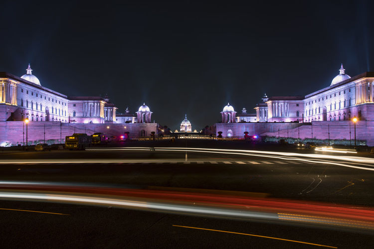 Light trails on road against buildings at night